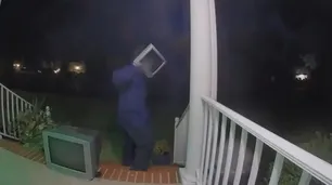 Un hombre con un televisor en la cabeza deja monitores antiguos en las puertas de las casas